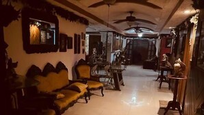 A dimly lit room with a sofa, chairs, and a ceiling fan.