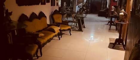 A dimly lit room with a sofa, chairs, and a ceiling fan.
