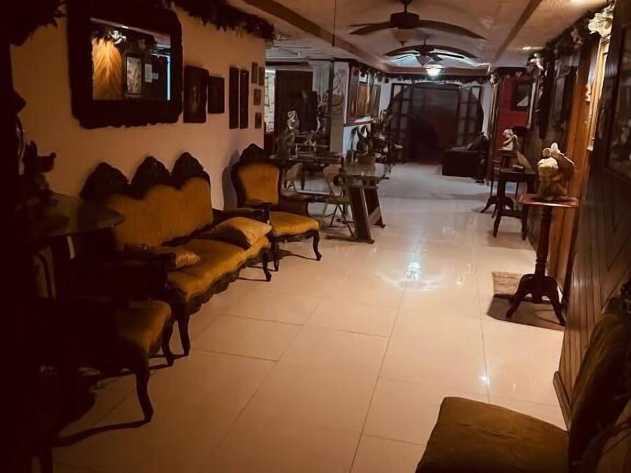 A dimly lit room with a sofa, chairs, and a ceiling fan.
