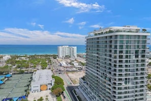 Ein Hochhaus-Hotel mit mehreren Balkonen, einem Parkplatz und Blick aufs Meer.