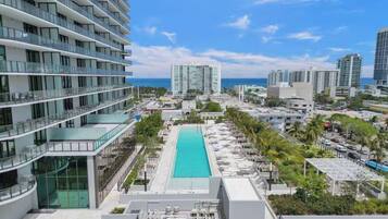 A high-rise hotel with a rooftop pool, multiple balconies, and a view of the ocean.