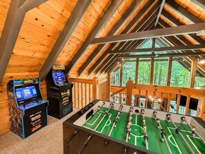 Ein Holzinterieur mit einem Kicker und zwei Spielautomaten.