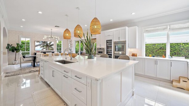 A spacious kitchen with white cabinetry, a large island, and pendant lighting. - 4BR Private Family Compound Heart of Delray Beach (Delray Beach)