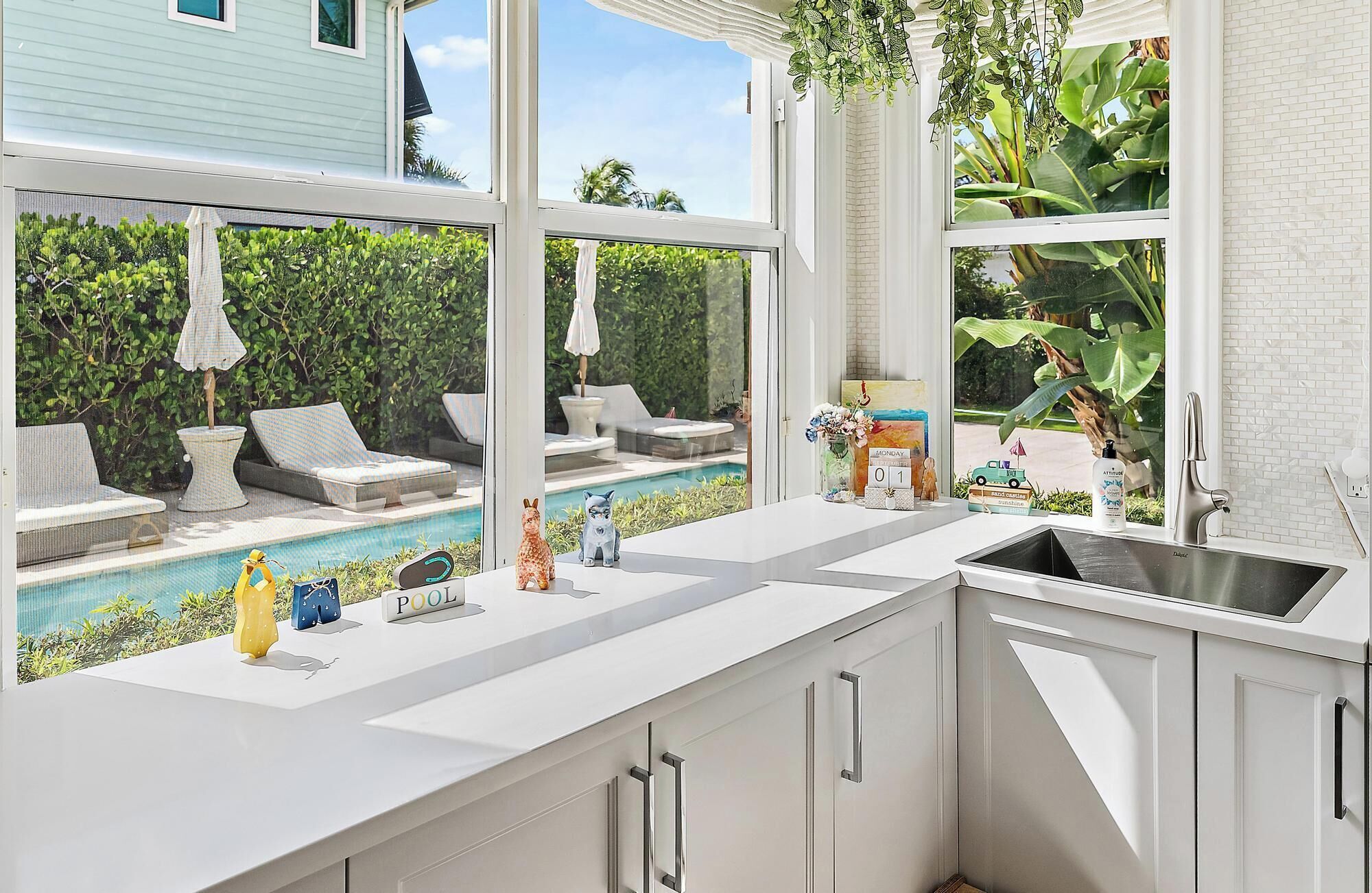 A modern kitchen with a large window overlooking a pool and outdoor seating area.