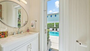 A bathroom with a large mirror, a sink, and a door leading to a pool area. - 4BR Private Family Compound Heart of Delray Beach (Delray Beach)
