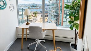 Een moderne kantoorruimte met uitzicht op een stadsgezicht, een bureau met stoel, een lamp en een potplant.
