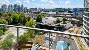 Een balkon met houten traptreden en uitzicht op een stadsgezicht met moderne gebouwen en een rivier.