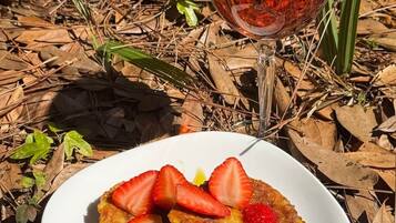 Une assiette de nourriture avec des fraises et un verre de boisson rouge, le tout posé sur un sol recouvert de feuilles.