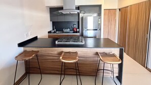 Una cocina moderna con una isla central, taburetes de bar, estufa y refrigerador.