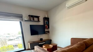 Una sala de estar moderna con un sofá, televisor y estanterías.