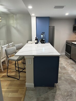 A kitchen with a central island, a refrigerator, a microwave, and a sink. - Newly remodeled Beachfront 2BR-2Bath Condo / Pool & Gulf Views (Fort Myers Beach)