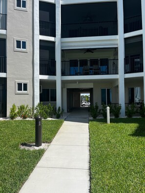 A multi-story residential building with a central courtyard, balconies, and a covered entrance. - Newly remodeled Beachfront 2BR-2Bath Condo / Pool & Gulf Views (Fort Myers Beach)
