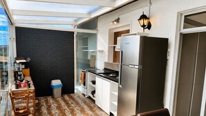 A compact kitchen with a refrigerator, stove, and dining area with chairs and a table. - Penthouse with ocean view, one block from the beach, with private garage. (Florianópolis)