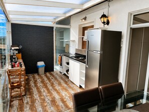 Eine kleine Küche mit Kühlschrank, Herd und Essbereich mit Stühlen und Tisch.