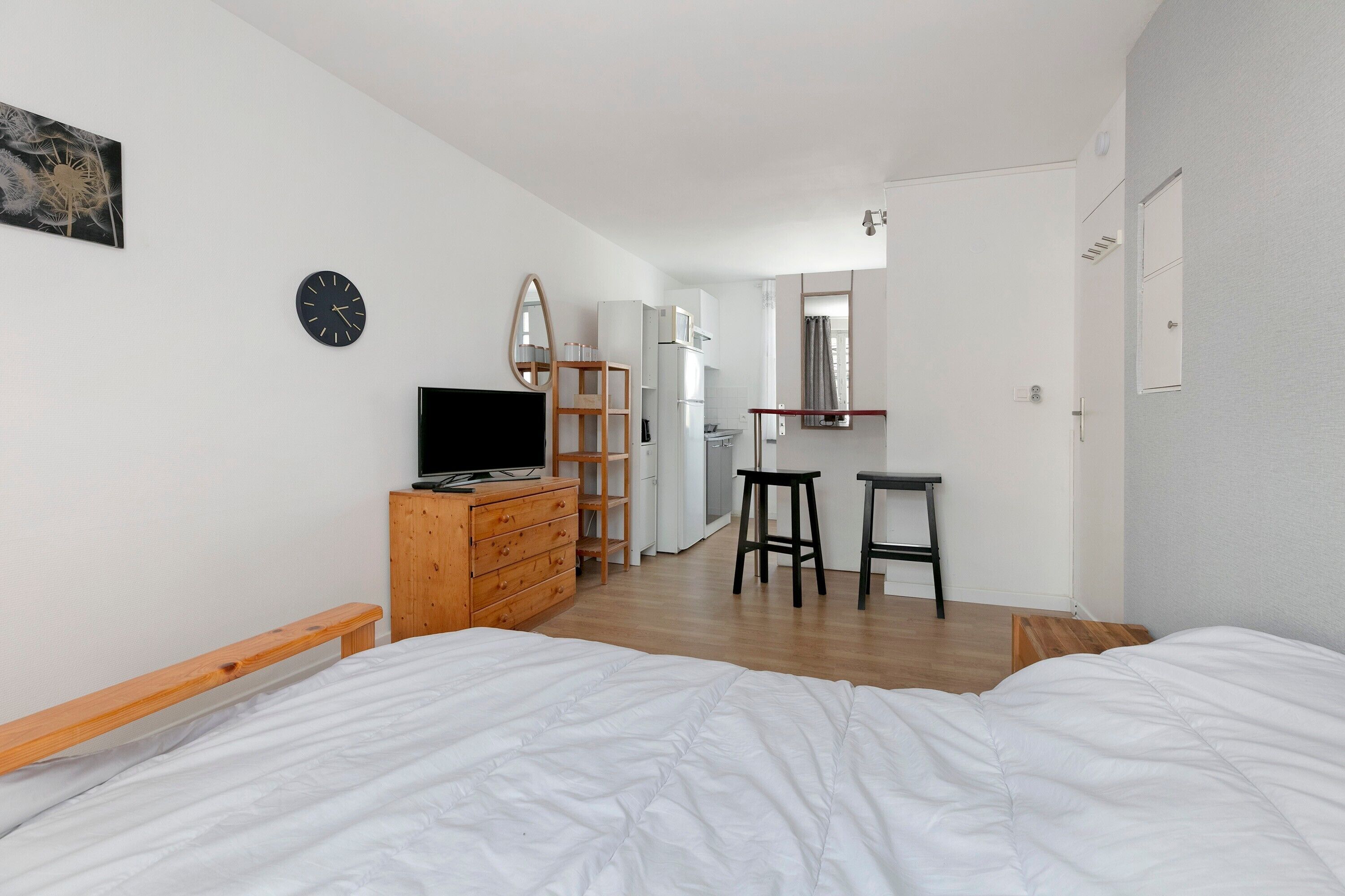 A bedroom with a bed, a dresser, a TV, a mirror, and a bathroom visible in the background.