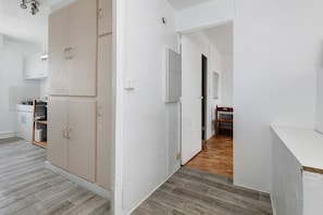 A modern kitchen with white cabinets, a wooden floor, and a view into the dining area.