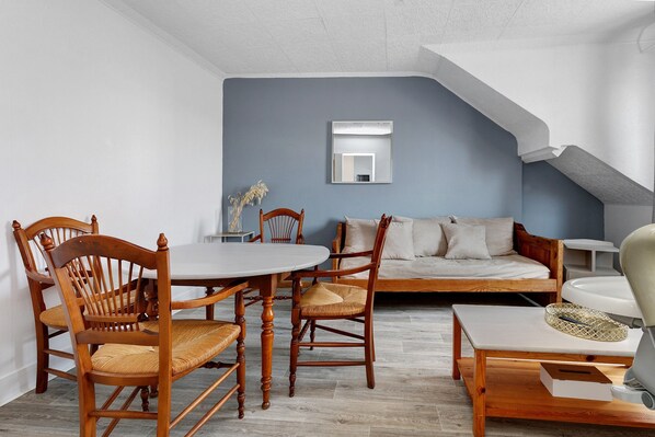 A room with a dining table, chairs, a sofa, and a bed.