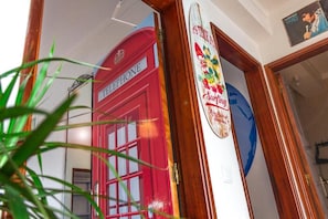 A red telephone booth with a sign that reads 'TELEPHONE' and a surfboard with the text 'Surfing Forever' in the background.