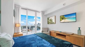 A hotel room with a bed, a desk, a chair, a TV, and a city view. - 1BR  Intracoastal View - Resort & Pool (Hallandale Beach)