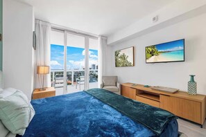A hotel room with a bed, a desk, a chair, a TV, and a city view. - 1BR  Intracoastal View - Resort & Pool (Hallandale Beach)