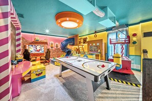 Ein Kinderspielbereich mit einem Tischfußballtisch, einer Rutsche und einer Ziegelwand im Hintergrund.