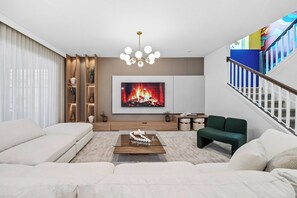 Ein modernes Wohnzimmer mit Kamin, einer Couch, einem Couchtisch und einer Treppe.
