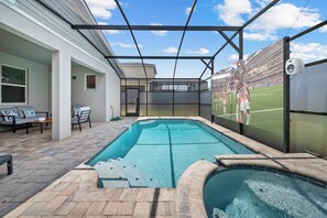 Ein Swimmingpool mit überdachter Terrasse, eine Sitzgelegenheit mit einer Couch und Sesseln sowie eine an der Wand montierte Überwachungskamera.
