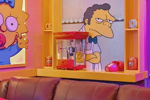 A Simpsons-themed room with a couch, a glass display case, and a shelf with salt and pepper shakers. - 6BR house sleeps 16 in kissimmee, fl (Kissimmee)