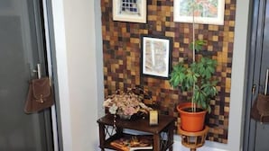 A hallway with a checkered wall, framed pictures, a potted plant, and a small table with a vase. - Casa da Floresta (Covilha)