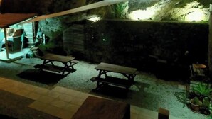 An outdoor dining area with picnic tables, a covered seating area, and a stone wall. - Casa da Floresta (Covilha)
