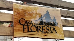 A wooden sign with the text 'CAS FLORESTA FOREST HOUSE' and a silhouette of a mountain and trees. - Casa da Floresta (Covilha)