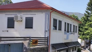 A two-story building with a red roof, a stone wall, and a gated entrance. - Casa da Floresta (Covilha)