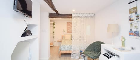 A modern bedroom with a bed, a desk, a chair, a TV, and a wall with pictures.