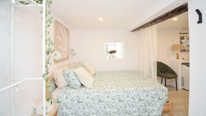 A bedroom with a bed, a chair, a desk, and a window with a plant. - Alma D'Alfama (Lisboa)