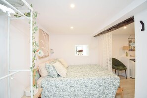 A bedroom with a bed, a chair, a desk, and a window with a plant. - Alma D'Alfama (Lisboa)