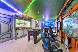 A room with a foosball table, a large screen, and gaming chairs. - 10BR house with game room near Disney area (Davenport)