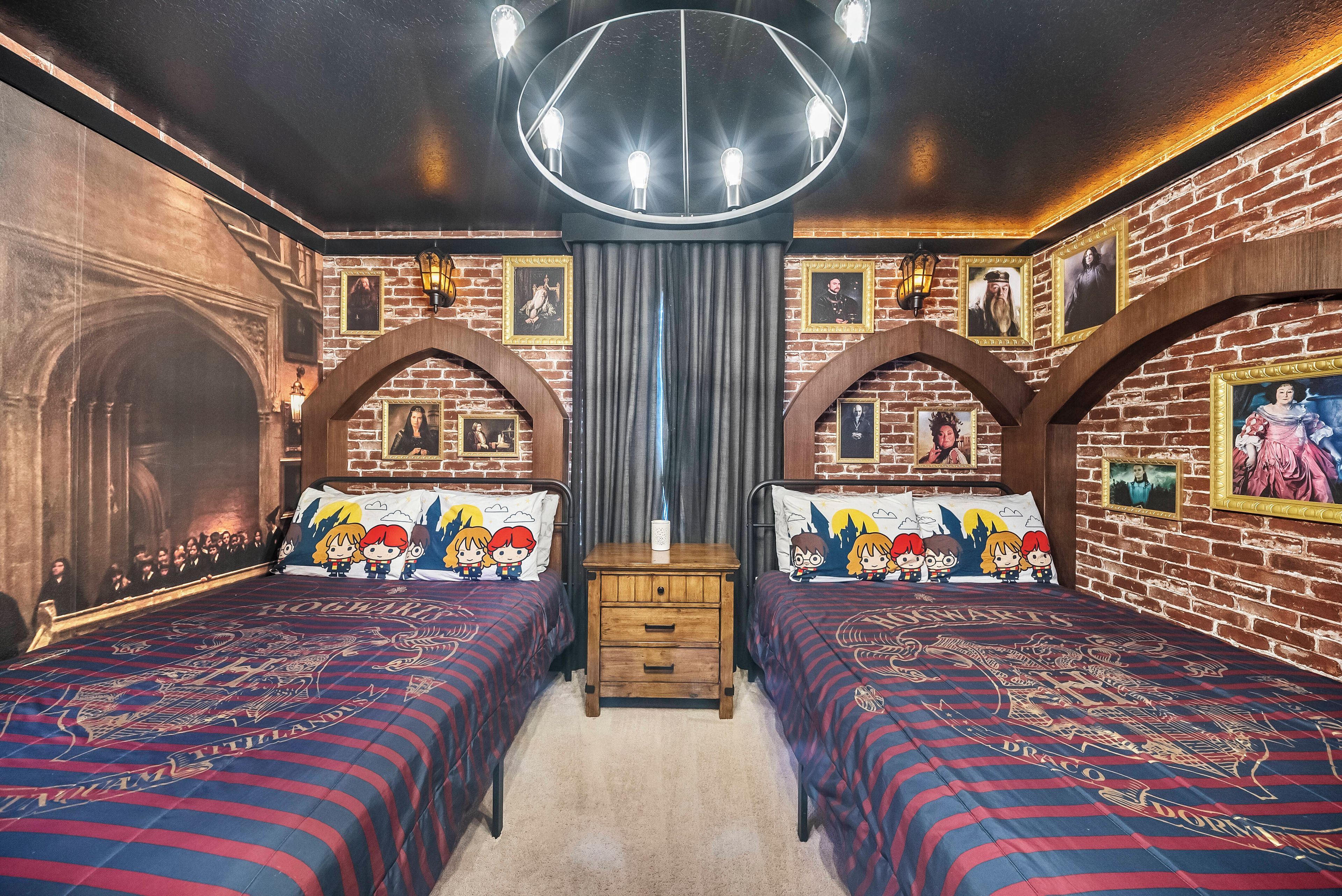 A room with two beds, a wooden dresser, and a chandelier.