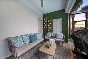 A patio area with a sofa, a coffee table, and a grill. - 10BR house with game room near Disney area (Davenport)