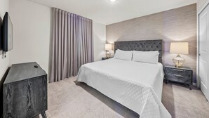 Hotellihuone, jossa on sänky, kaksi yöpöytää, televisio ja verho.