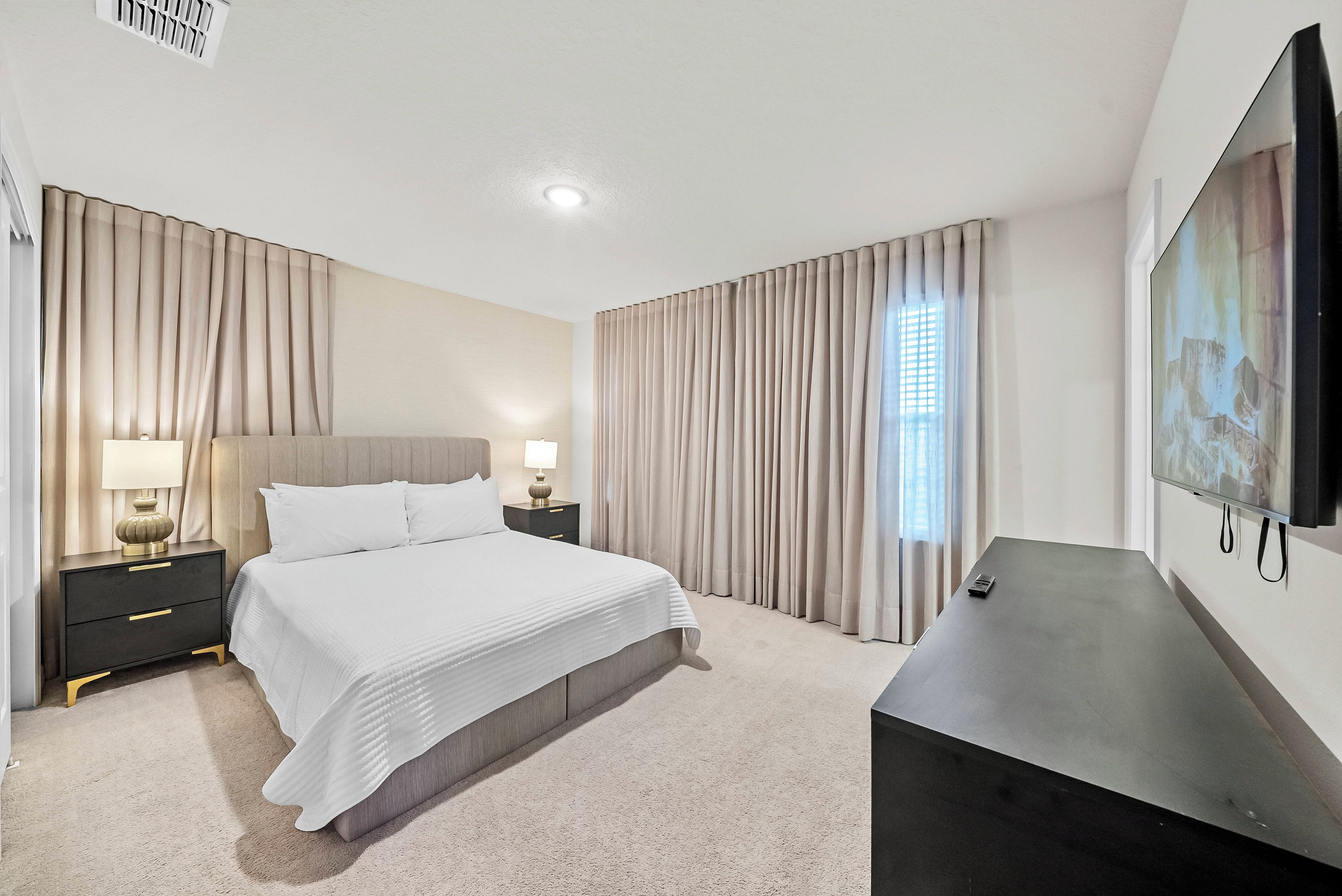Een hotelkamer met een bed, nachtkastjes, een televisie en gordijnen.