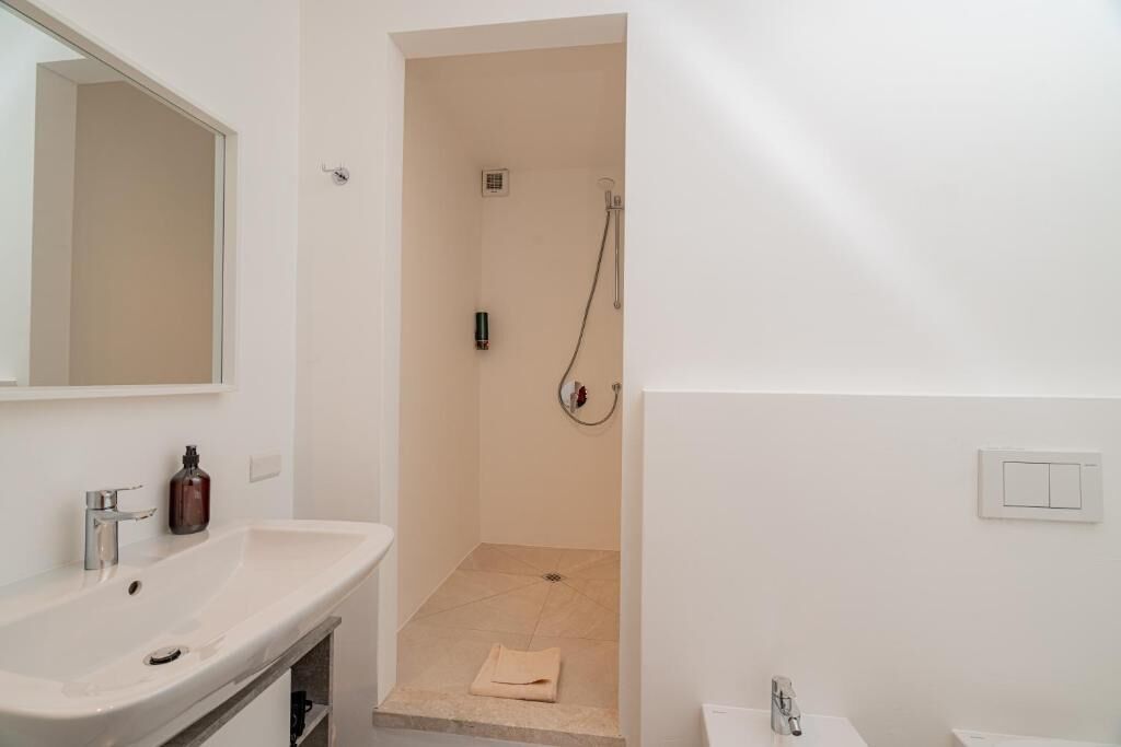 A bathroom with a white sink, mirror, and shower.