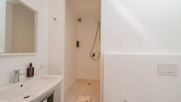A bathroom with a white sink, mirror, and shower.