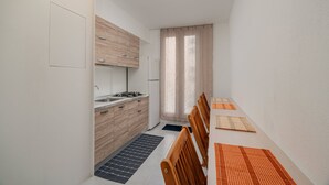 Cocina compacta con estufa a gas, un lavamanos y armarios de madera.