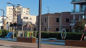 Un parque infantil con tobogán y estructuras para escalar, una banca y pavimento estampado.