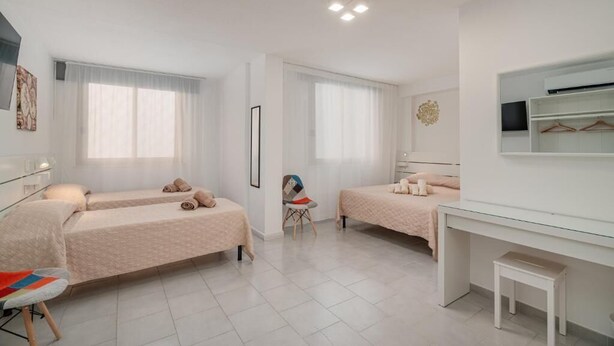 Habitación de hotel con dos camas, un escritorio, una silla y un televisor.