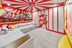 Ein Zimmer mit einer großen Wandmalerei von Zeichentrickfiguren, einem Sofa und einem kleinen Tisch.