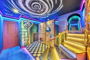 A vibrant hallway with a spiral ceiling design, a checkered floor, and a staircase with a golden railing. - 9BR house with private pool at Solara Resort\Racing Simulator (Kissimmee)