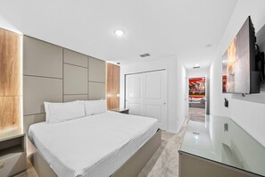 A modern bedroom with a large bed, built-in wardrobe, and a flat-screen TV mounted on the wall. - 9BR house with private pool at Solara Resort\Racing Simulator (Kissimmee)