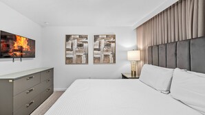 A hotel room with a bed, a dresser, a television, and two paintings on the wall. - 9BR house sleeps 18 with spa and private pool\Racing Simulator (Kissimmee)