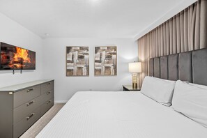 Ein Hotelzimmer mit einem Bett, einem Schminktisch, einem Fernseher und zwei Bildern an der Wand.
